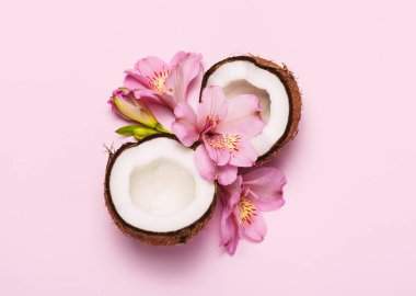 Pembe arka plan üzerinde tropik çiçekler ile Kırık hindistan cevizi.