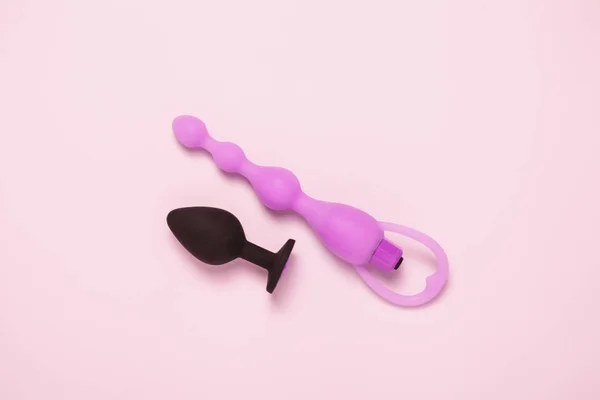 Konfeti ile pembe arka plan yetişkin seksi oyuncak anal fiş. Üst görünüm, düz yatıyordu.