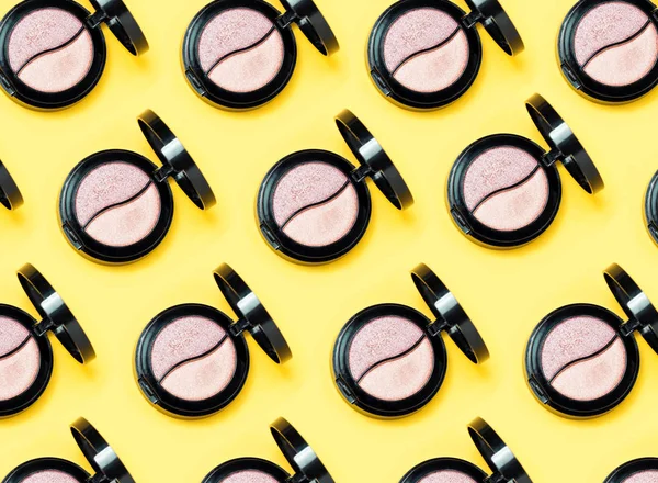 Paletas de tres sombras de ojos y varios pinceles de maquillaje sobre fondo amarillo . — Foto de Stock