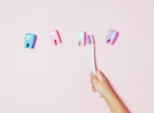 Kind handen met grote tand en tandenborstel op roze backgroubd. Gezonde zorg tanden concept. Bovenaanzicht, plat lag. Ruimte voor uw tekst kopiëren. — Stockfoto