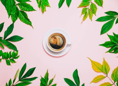 Pembe arka plan üzerinde kapuçino ve tropik yaprakları Fincan.