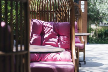 Kafedeki bir verandada pembe yastıklı hasır sandalye. Güzel güneş ışığı..