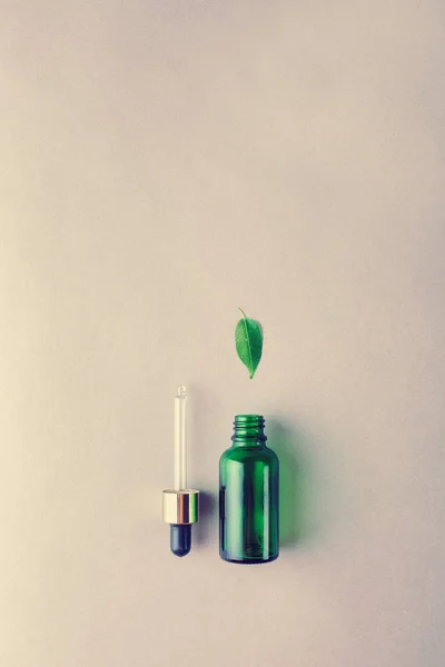 The minimal style. Natural skin care, cosmetics. Eco. Green glass bottle with a pipette in pastel colors. Flat lay.