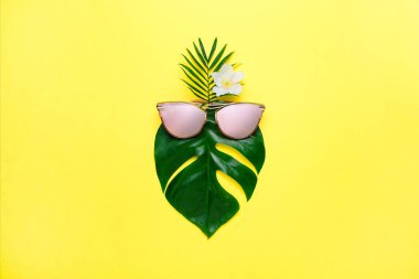 Tropikal yaz konsepti. Moda hippi Monstera trendy gözlük. Yaratıcı poster, parlak sarı arka plan.