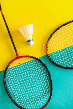 Raketle ve sarı bir arka plan üzerinde badminton oynamak için raket. Minimalizm. Kavram yaz razlecheny.
