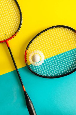 Raketle ve sarı bir arka plan üzerinde badminton oynamak için raket. Minimalizm. Kavram yaz razlecheny.