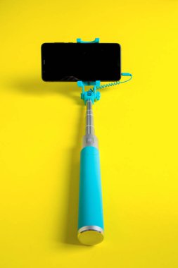 Monopod ile akıllı telefon selfie için. Selfie sopa ile smartphone üzerinde sarı arka plan izole