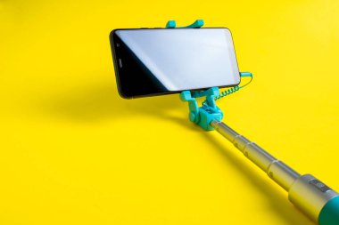 Monopod ile akıllı telefon selfie için. Selfie sopa ile smartphone üzerinde sarı arka plan izole