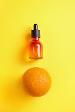 Cam şişe ve turuncu sarı bir arka plan üzerinde. C vitamini ile organik bio kozmetik Minimalizm düz kavramı yatıyordu
