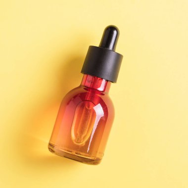 Cam şişe kozmetik, serumlar ve sarı bir arka plan üzerinde bir pipet ile yağlar için.