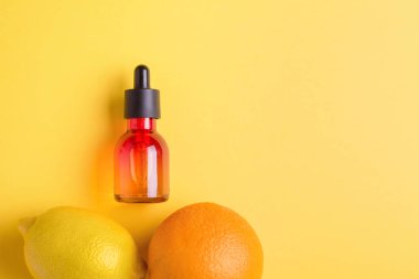 Cam şişe, portakal, limon sarı bir arka plan üzerinde. Organik bio kozmetik vitamin C. kavram minimalizm düz ile yatıyordu