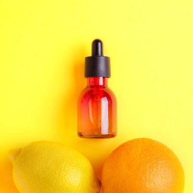 Cam şişe, portakal, limon sarı bir arka plan üzerinde. Organik bio kozmetik vitamin C. kavram minimalizm düz ile yatıyordu