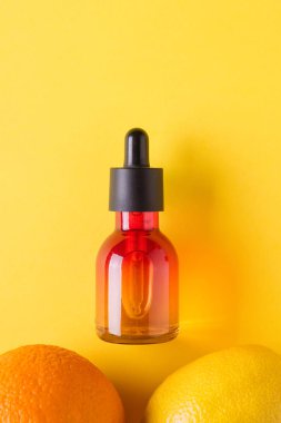 Cam şişe, portakal, limon sarı bir arka plan üzerinde. Organik bio kozmetik vitamin C. kavram minimalizm düz ile yatıyordu