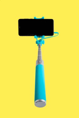 Monopod ile akıllı telefon selfie için. Selfie sopa ile smartphone üzerinde sarı arka plan izole