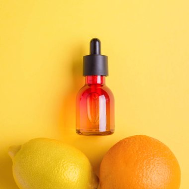 Cam şişe, portakal, limon sarı bir arka plan üzerinde. Organik bio kozmetik vitamin C. kavram minimalizm düz ile yatıyordu