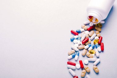 Eczacılık preparatları, arka plan. Renkli ilaçlar hap, tablet ve kapsüller kavanozdan dökülür. Tıp kavramı.