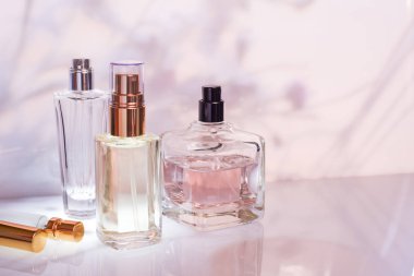 Parfüm şişesi açık pembe çiçek arka planı üzerinde. Seçici odak. Parfümeri koleksiyonu, kozmetik