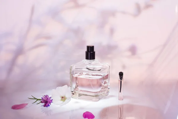香水瓶在一个浅粉色的花卉背景 选择性对焦 香水收藏 化妆品 — 图库照片