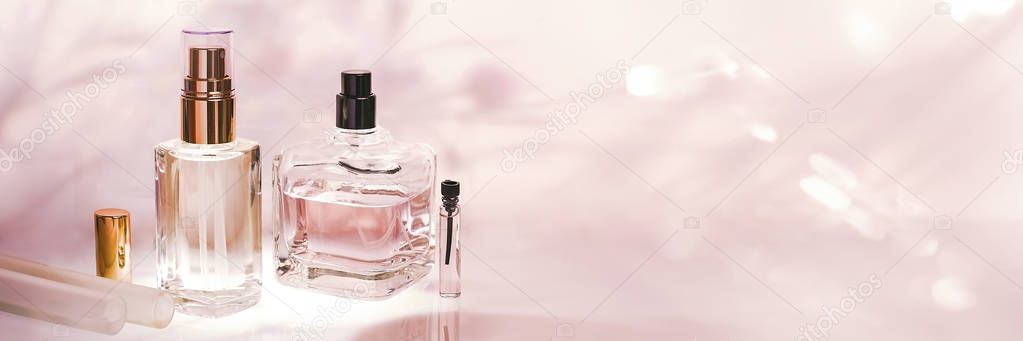 Perfume bottle on a light pink floral background. Selective focus. Perfumery collection, cosmetics.