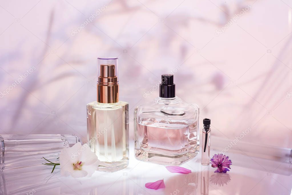 Perfume bottle on a light pink floral background. Selective focus. Perfumery collection, cosmetics.