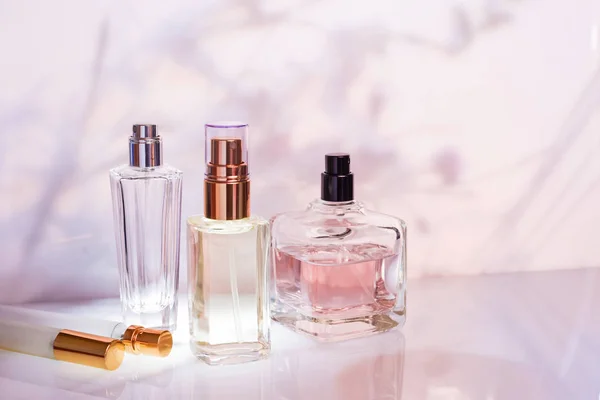 Bottiglia di profumo su uno sfondo floreale rosa chiaro. Concentrazione selettiva. Collezione di profumi, cosmetici — Foto Stock