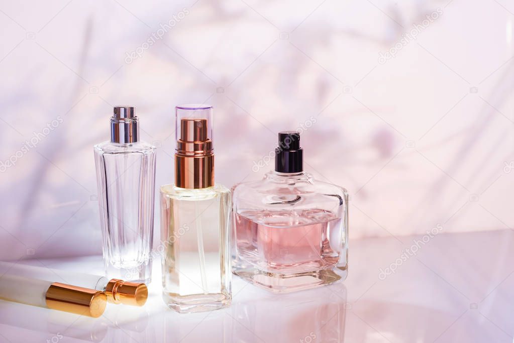 Perfume bottle on a light pink floral background. Selective focus. Perfumery collection, cosmetics