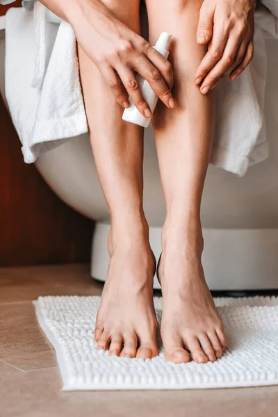 Body care. A young woman in the bathroom applies natural cream to her legs. Cosmetics and anti-cellulite care — Stock Photo, Image