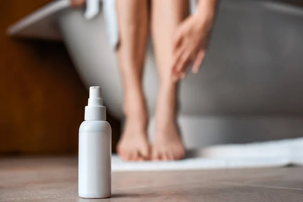 Body care. Young woman in the bathroom stroking her legs. Means against varicose veins and edema in the foreground. — Stock Fotó