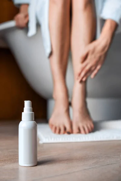 Cuidado com o corpo. Jovem mulher na casa de banho acariciando as pernas. Cosméticos para cuidados e anti-celulite em primeiro plano . — Fotografia de Stock