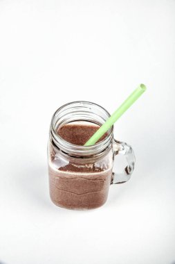 Taze protein içeceği, beyaz bir arka plan üzerinde bir cam kavanoza kakaolu süt