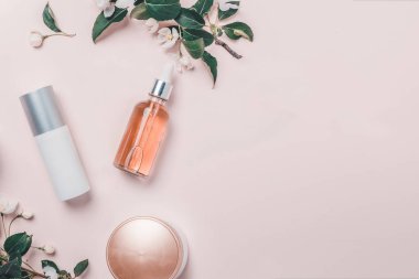 Pembe doğal kozmetik: petrol, serum, krem, maske çiçek zemin üzerine. Düz yatıyordu, minimalizm.