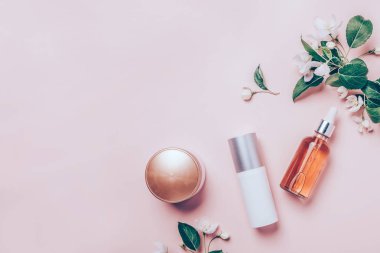 Pembe doğal kozmetik: petrol, serum, krem, maske çiçek zemin üzerine. Düz yatıyordu, minimalizm.