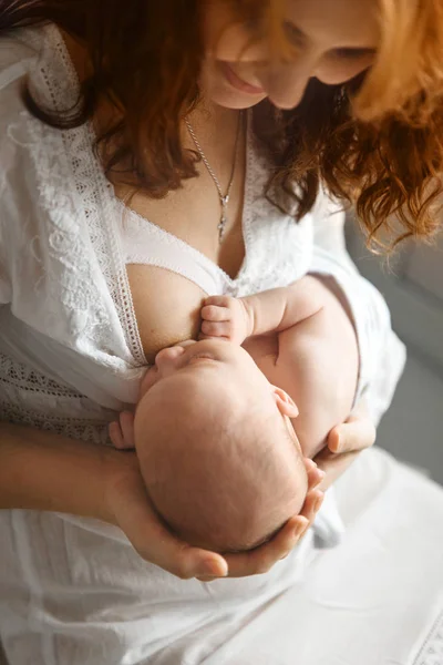 A amamentar. Bela mãe ruiva amamenta um bebê recém-nascido. Fotos de aparência natural — Fotografia de Stock
