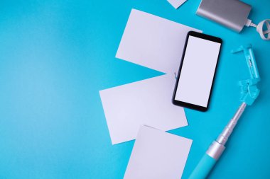 Boş ekrana ve mavi arka planda fotoğraflara sahip akıllı telefon. Alay, düz yatıyordu