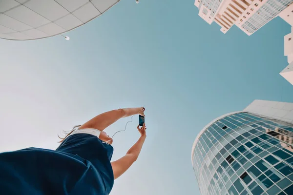 Una chica está tomando fotos de un nuevo complejo residencial rascacielos blancos modernos . — Foto de Stock