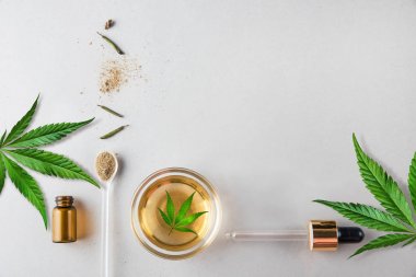 Arka planda Cbd yağı ve kenevir yaprağı ile cam yeşil şişe ve pipet. Minimal kavram. Düz yatıyordu.