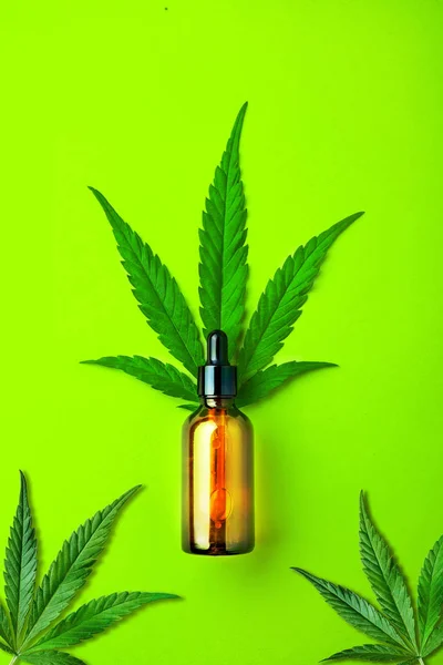 Glas brun flaska med CBD-olja och cannabisblad på grön bakgrund. Minimalt CBD-koncept. Flat Lay. — Stockfoto