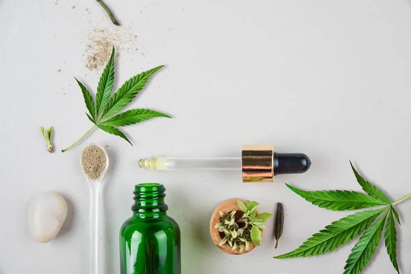 Glas grön flaska och pipett med CBD-olja och cannabisblad på bakgrunden. Minimalt koncept. Flat Lay. — Stockfoto