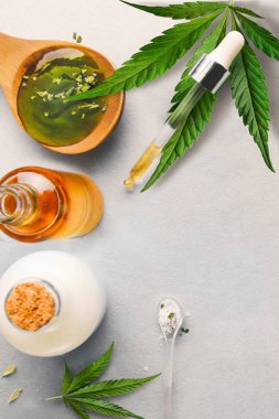 Cam şişe ve damlalık Cbd Yağı, Thc tentür ve arka planda kenevir yaprağı. Cbd yağı ile kozmetik üretimi.