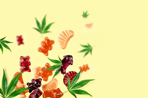 Színes gummies repülnek együtt a kannabisz levelek. Rágógumi cukorka, CBD olajjal, THC. kreatív háttér, minimalizmus. — Stock Fotó