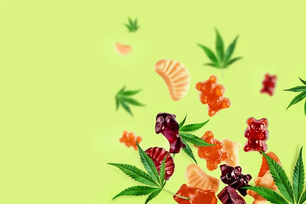 Gummies berwarna terbang bersama dengan daun ganja. Permen kunyah, permen karet dengan minyak CBD dan THC. Warna latar belakang kreatif, minimalisme . — Stok Foto