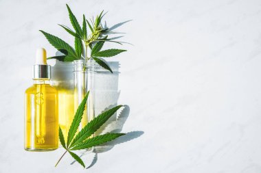 Kenevir yağı ile Cam şişe ve mermer bir arka plan üzerinde kenevir yaprakları ile bir test tüpü. Kopyalama alanı.