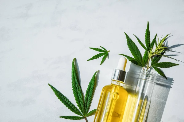 Glass bottle with cannabis oil and a test tube with hemp leaves on a marble background. Copy space. — Stock Photo, Image