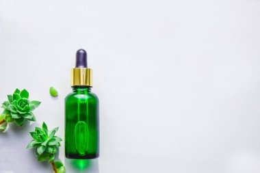 Pipetli cam yeşil şişedeki özlerden alınan doğal serum. Sulu, beyaz arka plan.