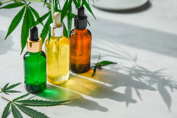 Different glass bottles with CBD OIL, THC tincture and cannabis leaves on yellow background. Flat lay — Stock Photo, Image