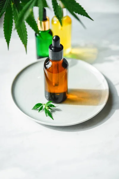 Glass bottle with cannabis oil with hemp leaves on a marble background. Copy space. — Stock Photo, Image