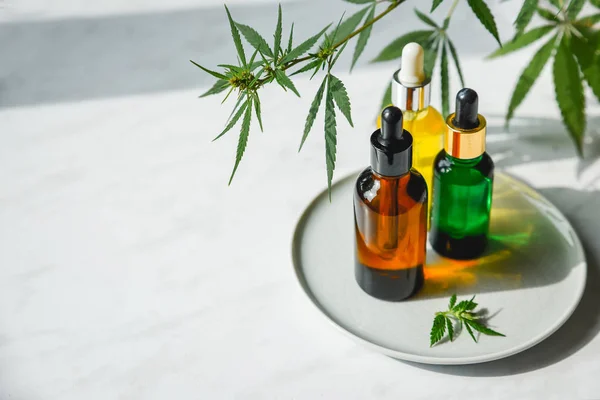 Cbd yağı ile Cam şişeler, Thc tentür ve kenevir mermer bir arka plan üzerinde yaprakları. Düz kozmetik kenevir yağı yatıyordu.