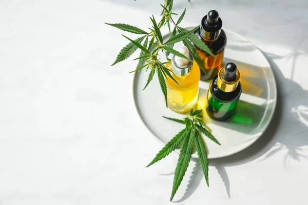 Diferentes garrafas de vidro com óleo de CBD, tintura de THC e folhas de cannabis no fundo amarelo. Depósito plano — Fotografia de Stock
