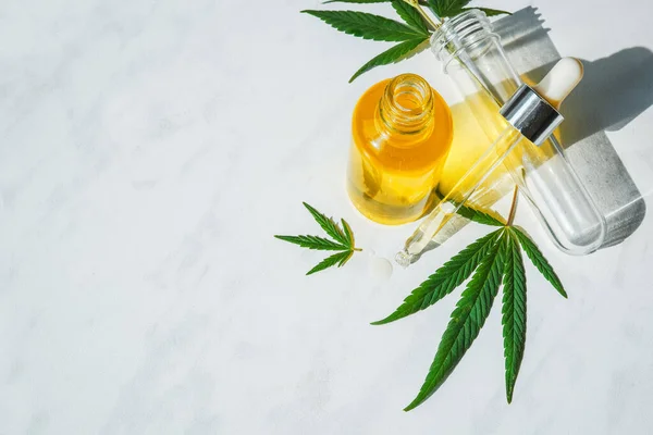 Botella de vidrio con aceite de cannabis y un tubo de ensayo con hojas de cáñamo sobre un fondo de mármol. Copiar espacio . —  Fotos de Stock