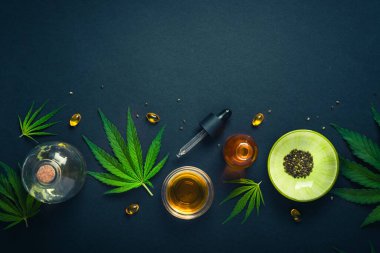 CBD yağı, siyah arka planda kenevir yapraklı tentür. Pipetli ve marihuana yapraklı farklı şişeler. Sağlık ve kozmetik için tıbbi esrar konsepti. Minimalizm.